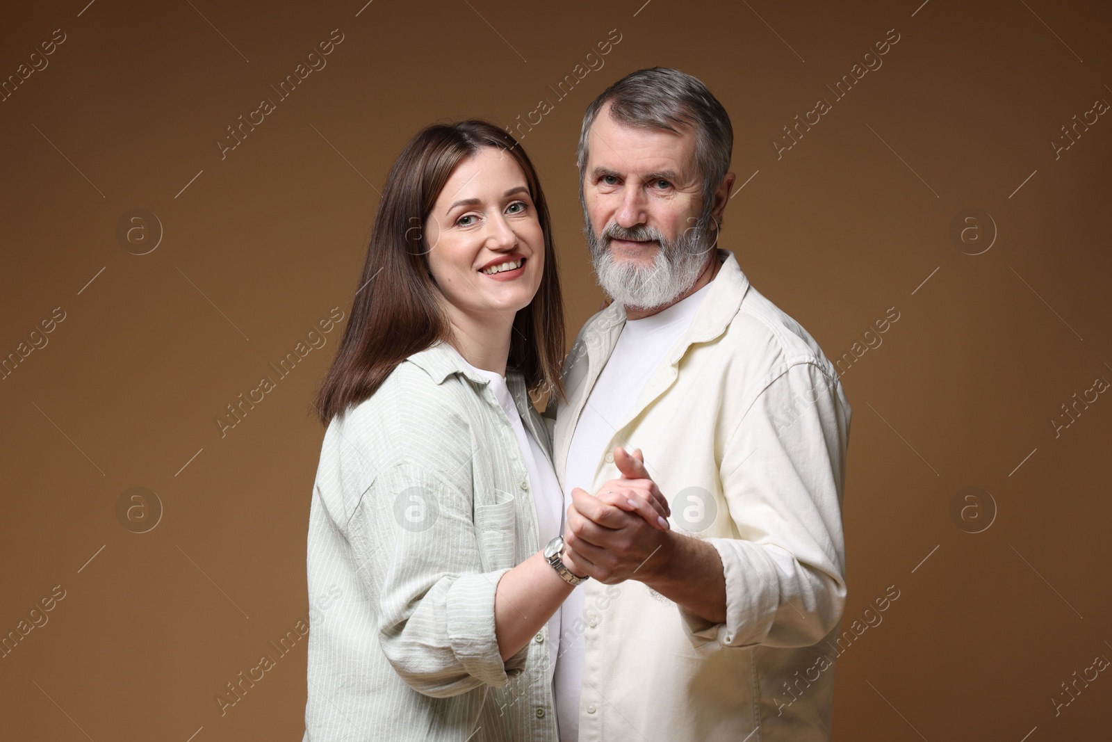 Photo of Happy daughter dancing with her father on brown background