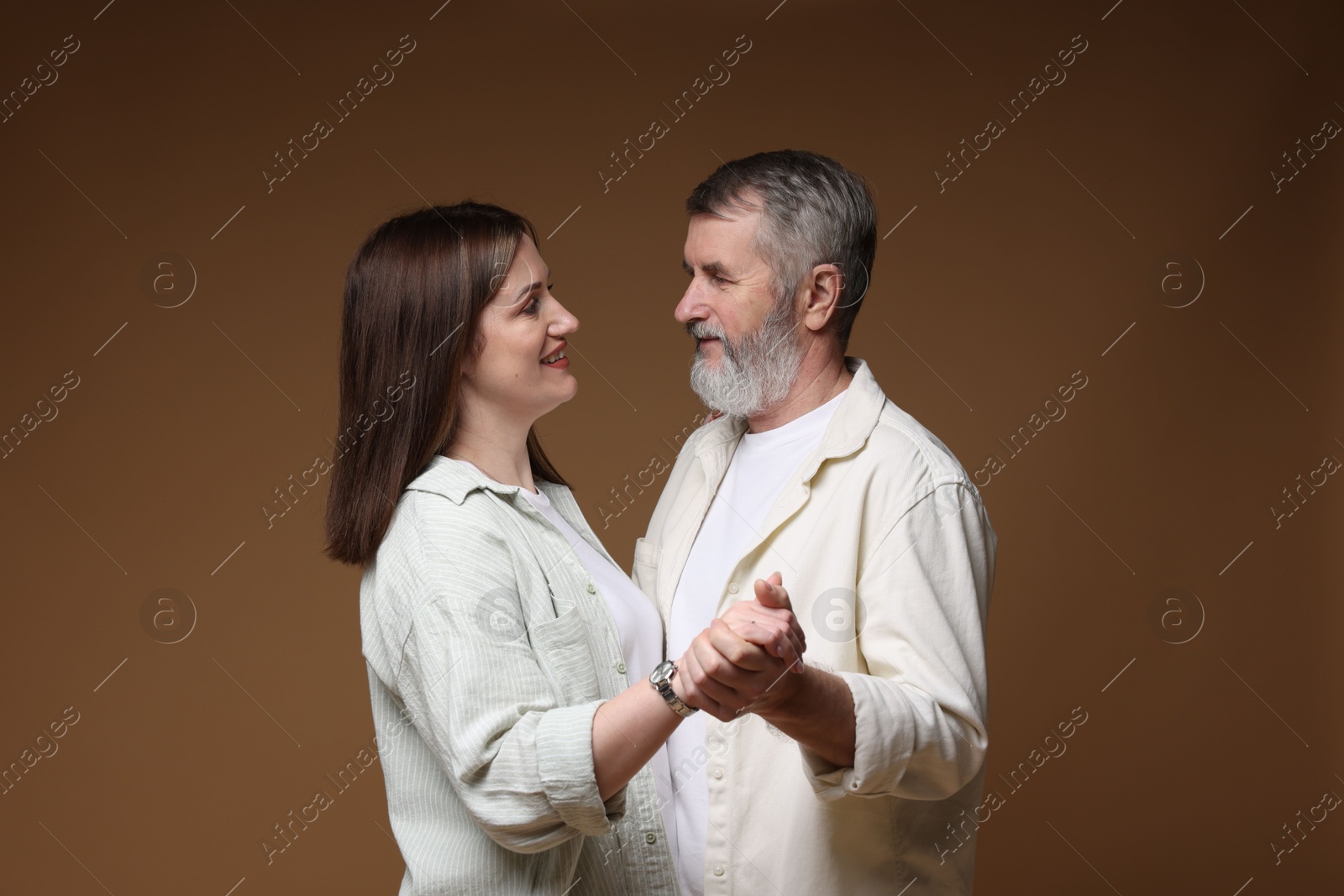 Photo of Happy daughter dancing with her father on brown background