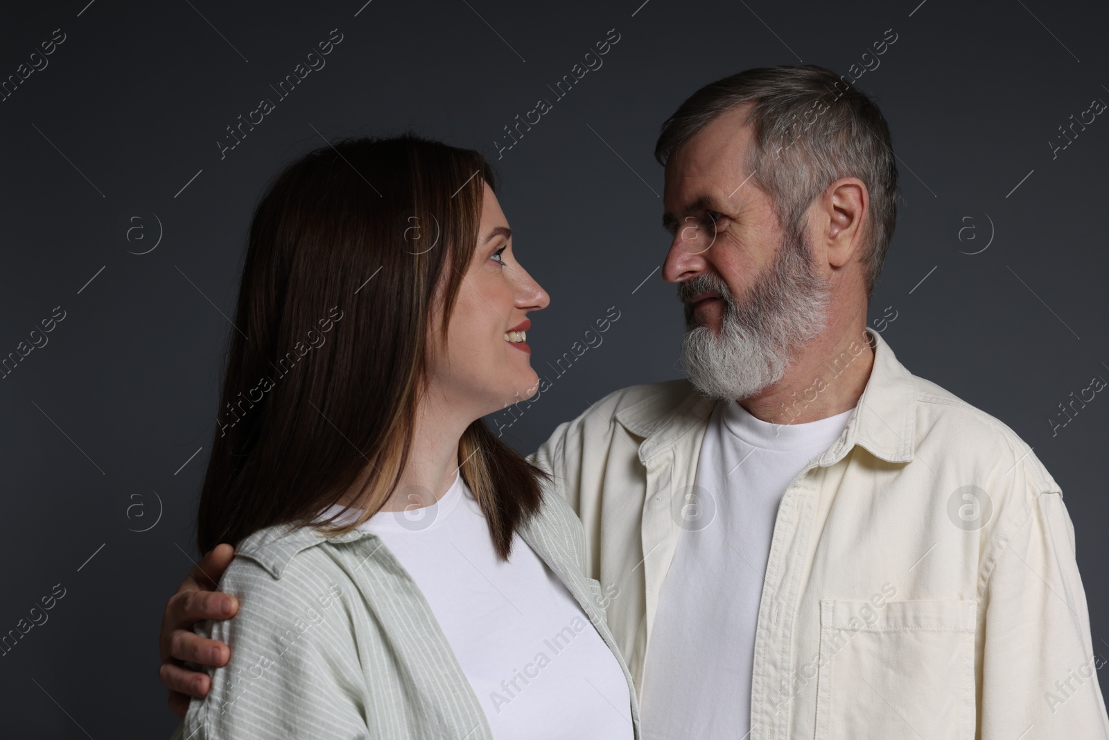 Photo of Happy daughter and her father looking at each other on dark background