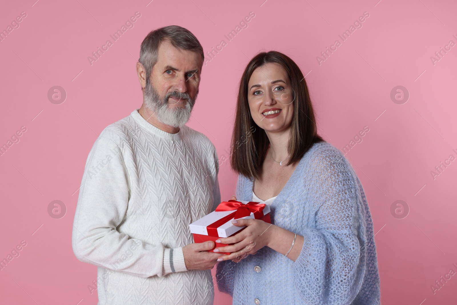 Photo of Family portrait of happy daughter and her father with gift on pink background