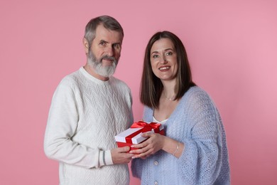 Photo of Family portrait of happy daughter and her father with gift on pink background