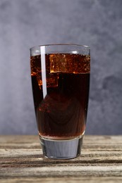 Photo of Sweet soda water with ice cubes in glass on wooden table