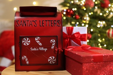 Photo of Santa Claus mailbox and gift boxes on wooden table indoors. Christmas tradition