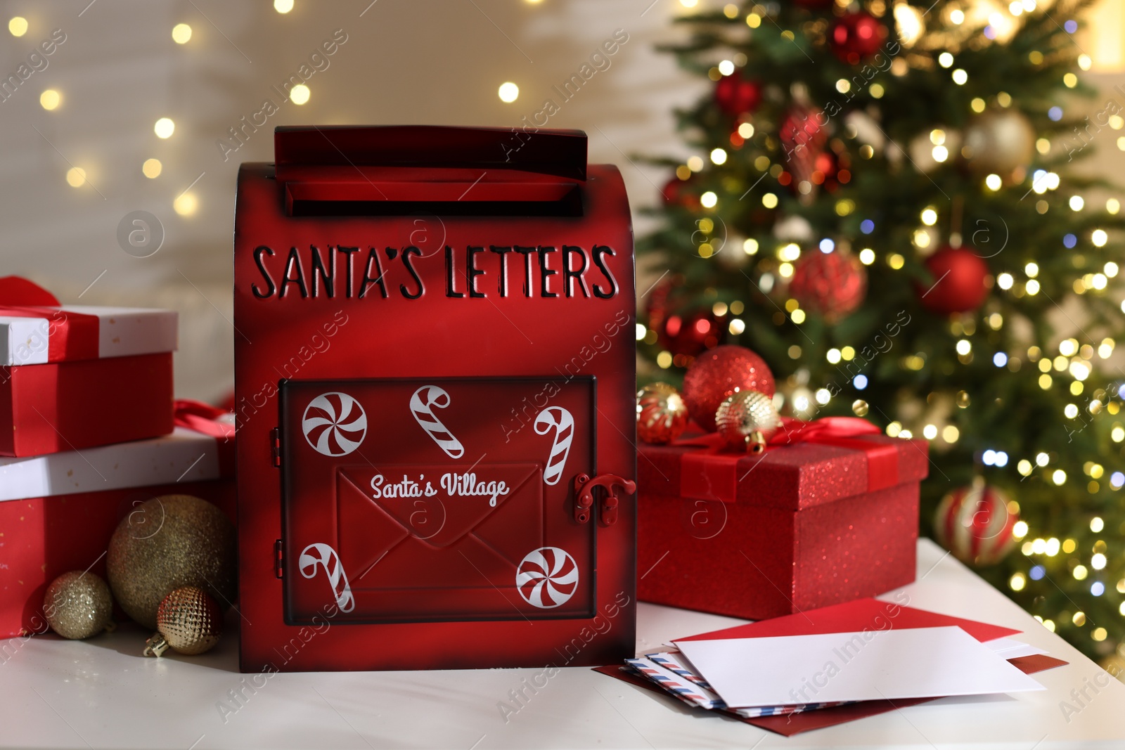 Photo of Santa Claus mailbox, letters, gift boxes and Christmas decor on white table indoors