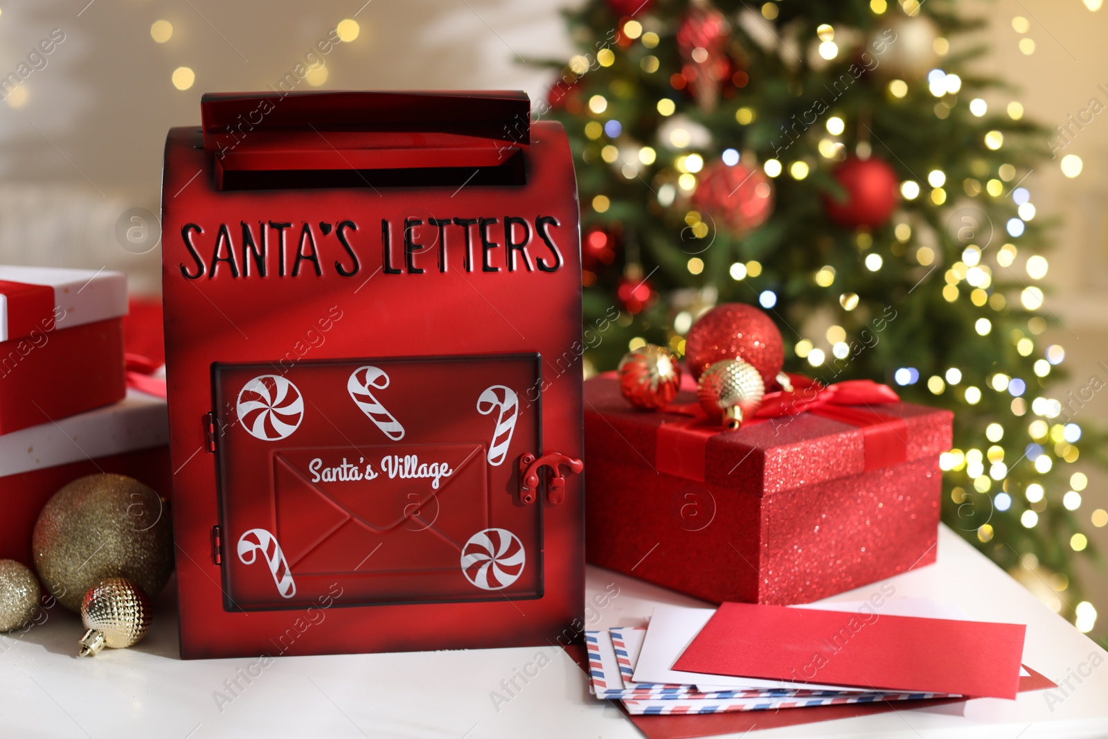 Photo of Santa Claus mailbox, letters, gift boxes and Christmas decor on white table indoors