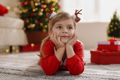 Photo of Little girl in Christmas costume lying on floor at home