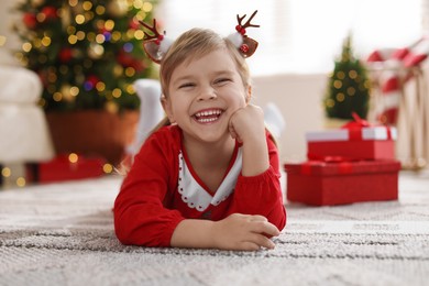 Photo of Little girl in Christmas costume lying on floor at home