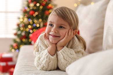 Photo of Little girl lying on sofa at home. Christmas celebration