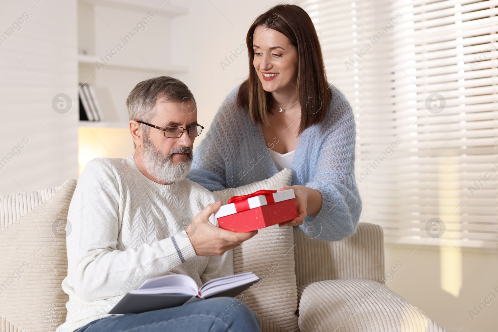 Photo of Happy daughter presenting her father with gift at home