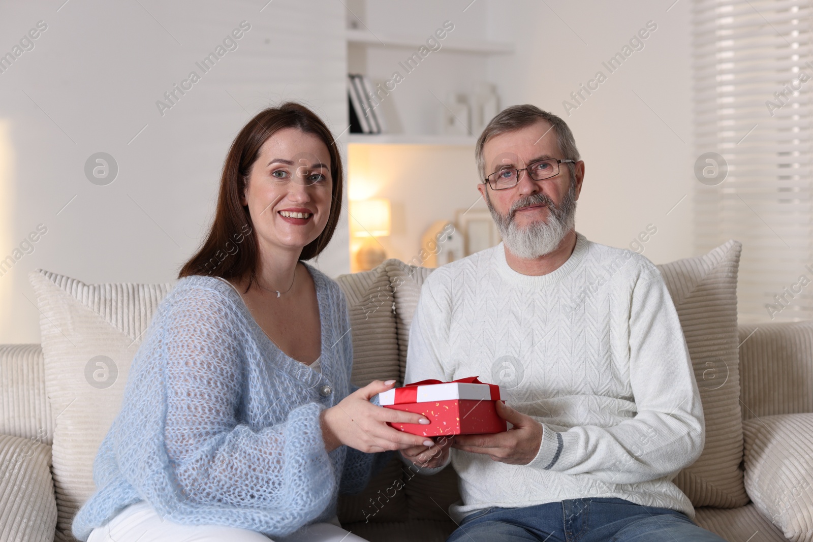 Photo of Family portrait of happy daughter and her father with gift at home