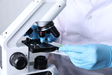 Photo of Laboratory testing. Scientist examining sample on slide under microscope indoors, closeup