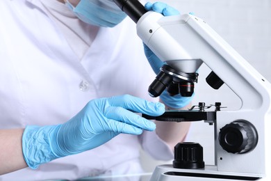 Photo of Laboratory testing. Scientist examining sample under microscope indoors, closeup