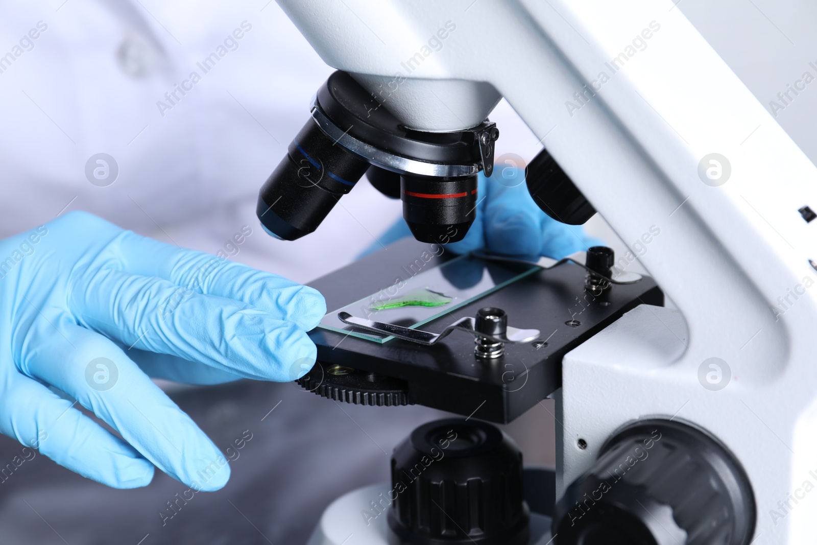 Photo of Laboratory testing. Scientist examining sample on slide under microscope indoors, closeup