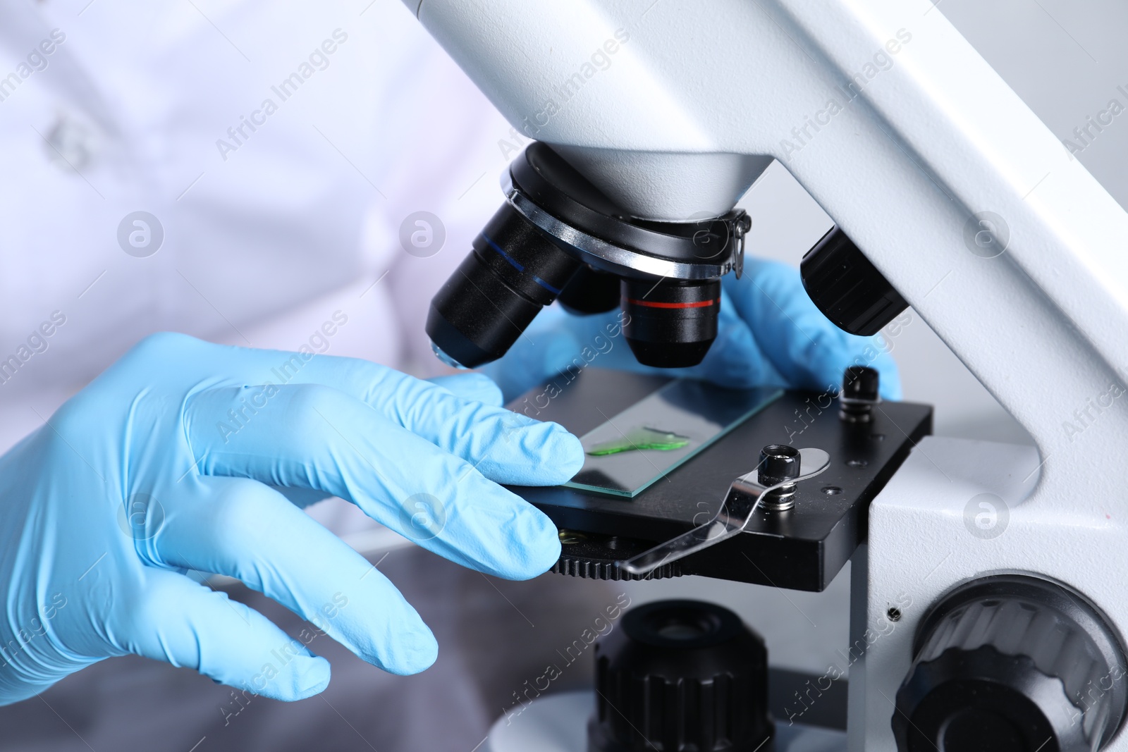 Photo of Laboratory testing. Scientist examining sample on slide under microscope indoors, closeup