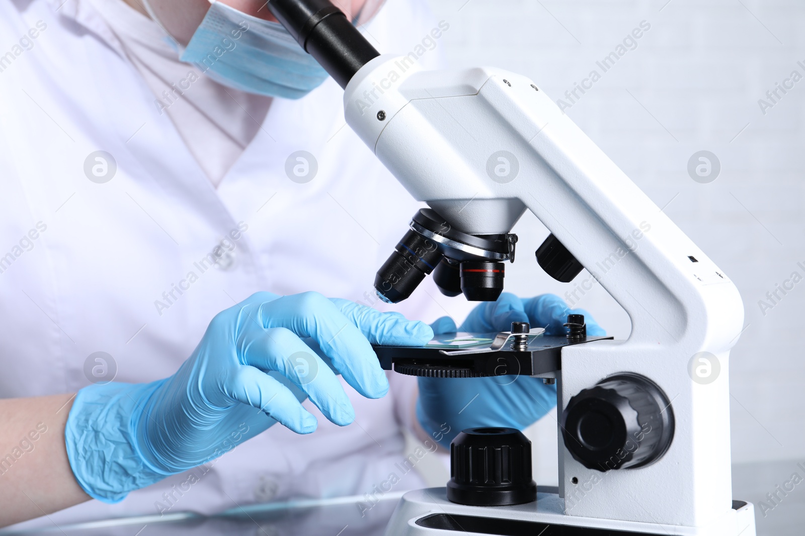 Photo of Laboratory testing. Scientist examining sample on slide under microscope indoors, closeup