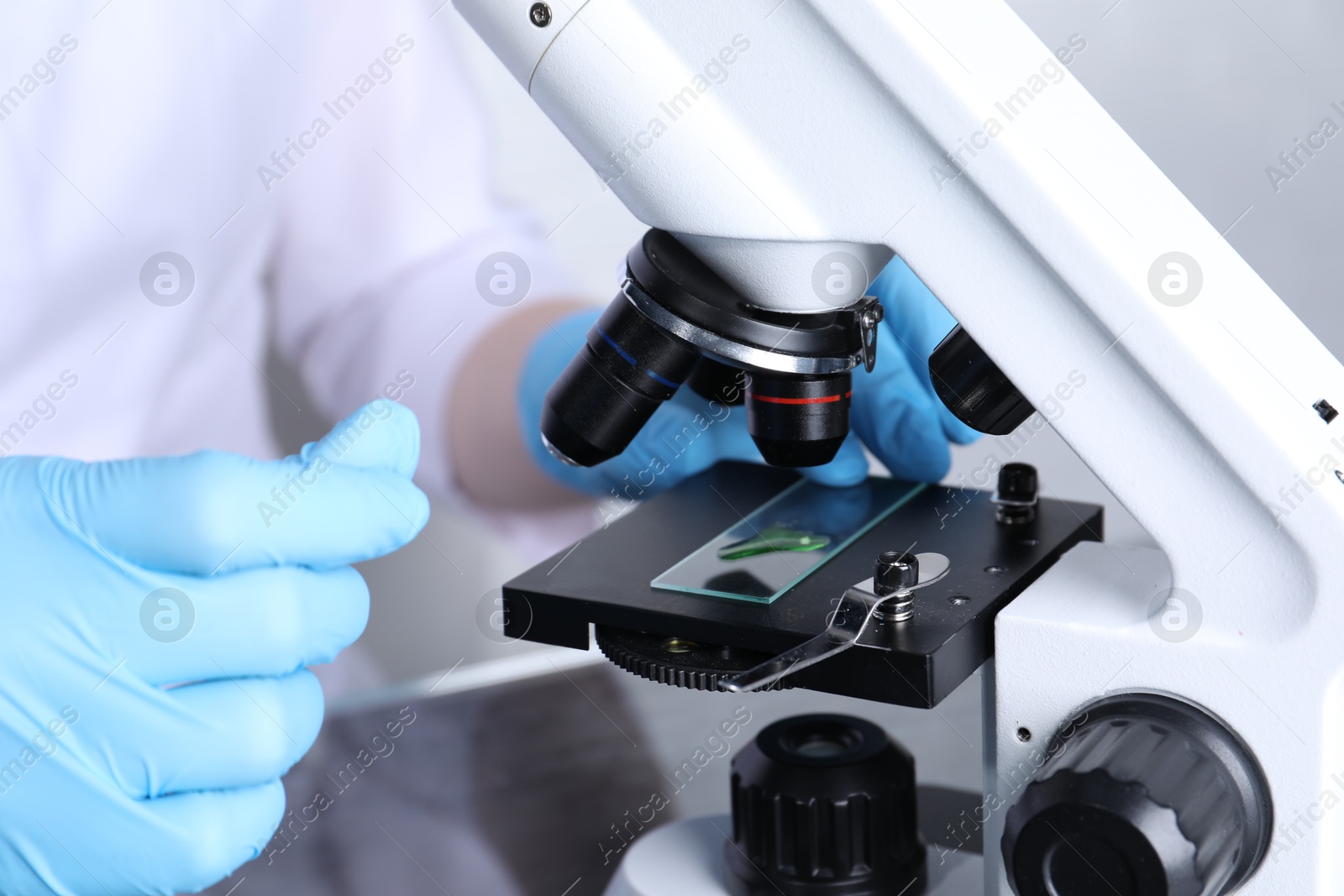 Photo of Laboratory testing. Scientist examining sample on slide under microscope indoors, closeup