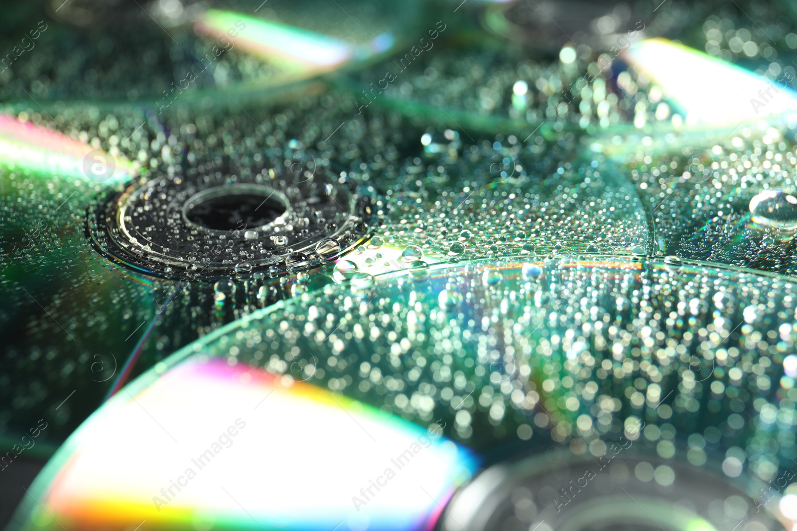 Photo of Compact discs with drops as background, closeup