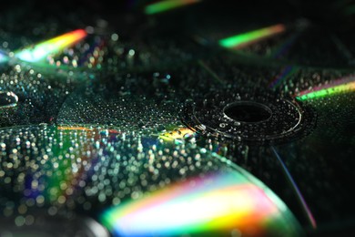 Photo of Compact discs with drops as background, closeup