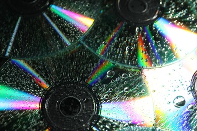 Photo of Compact discs with drops as background, closeup