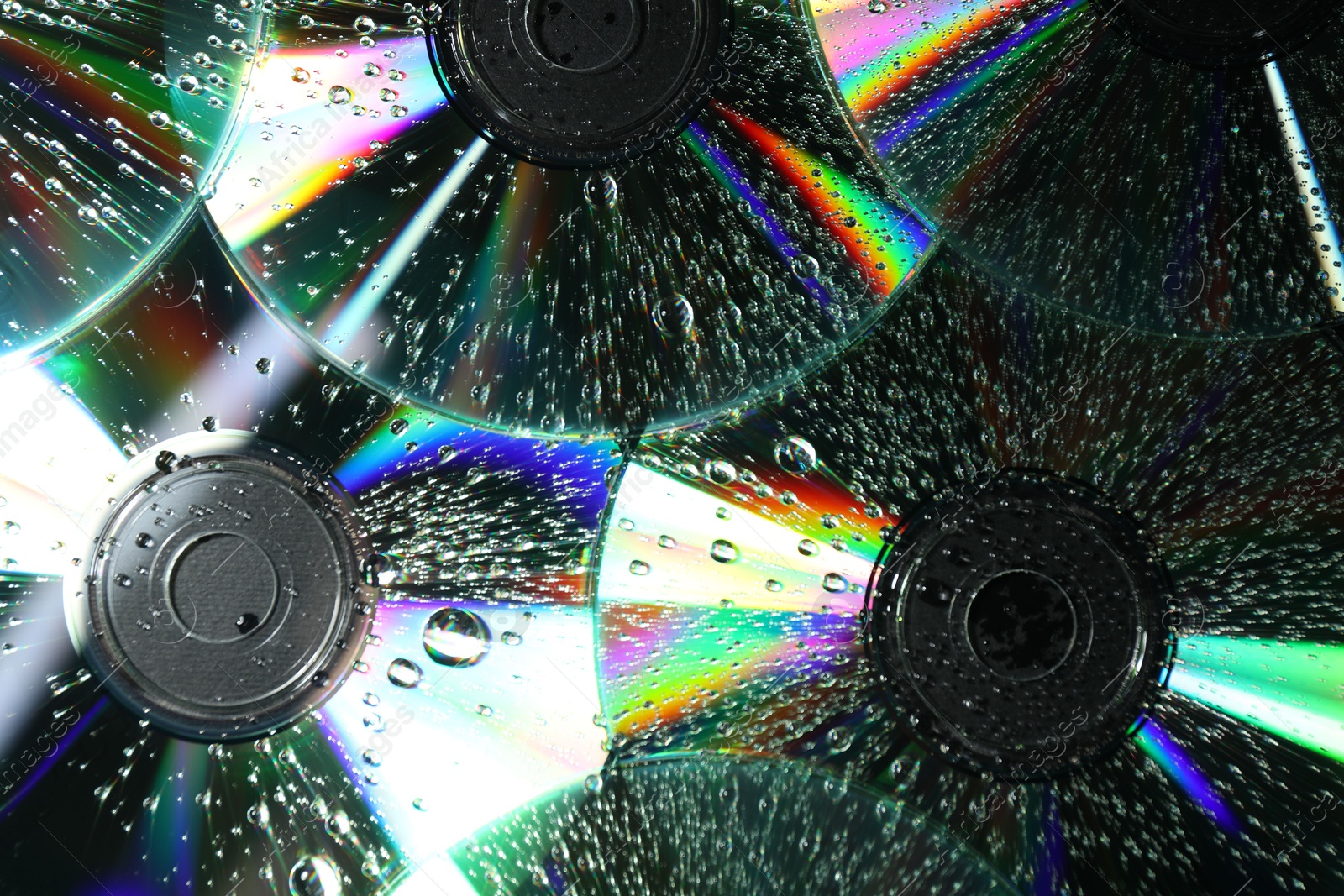 Photo of Compact discs with drops as background, closeup