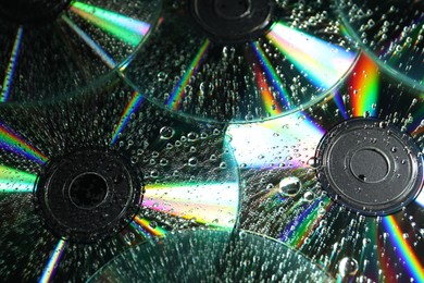 Photo of Compact discs with drops as background, closeup