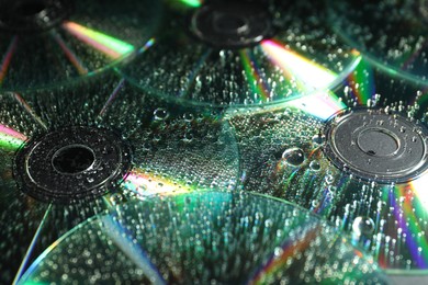 Photo of Compact discs with drops as background, closeup