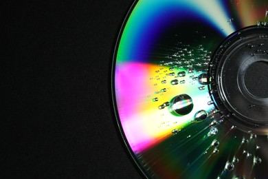 Compact disc with drops on black background, top view. Space for text