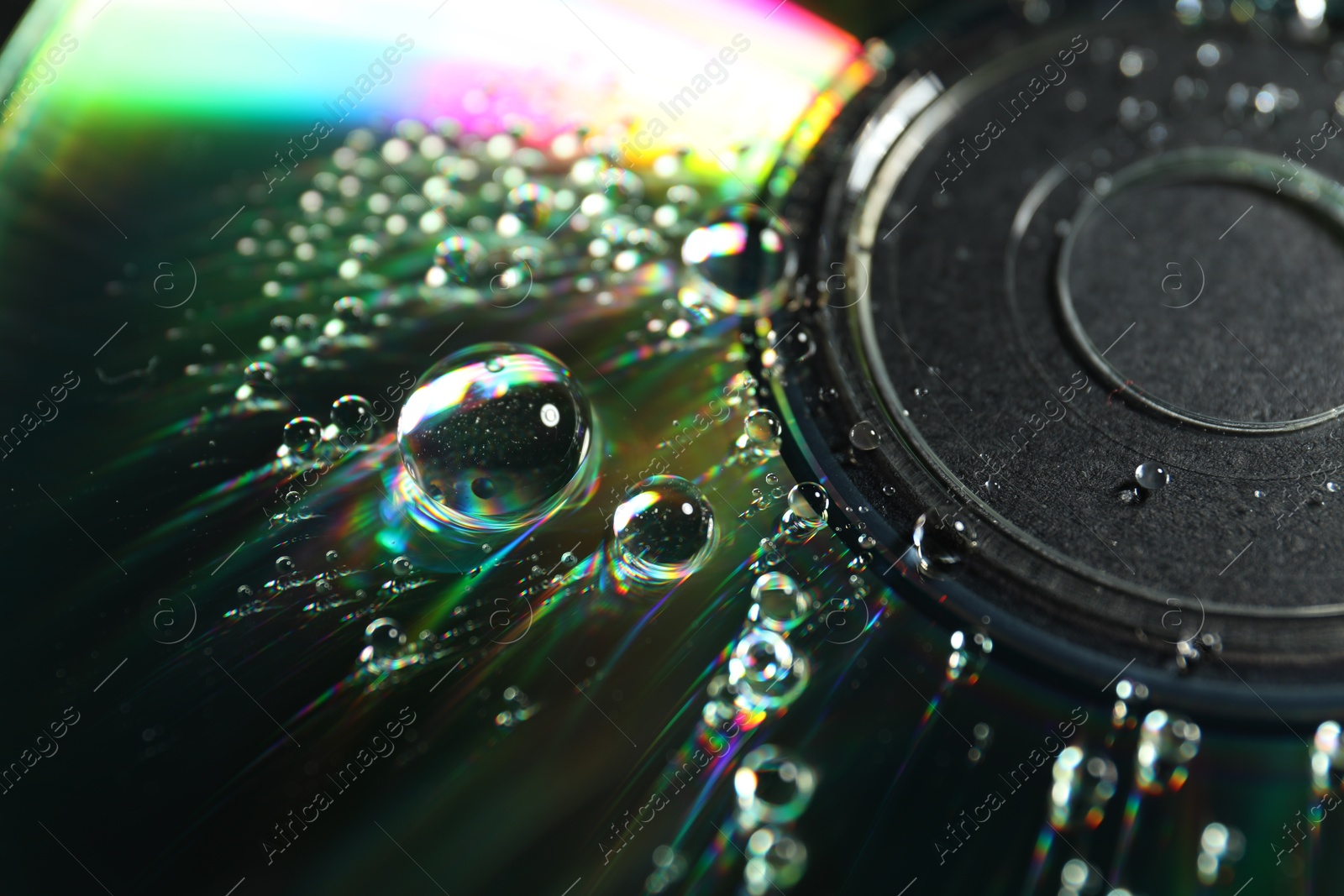 Photo of Compact disc with drops on black background, closeup view