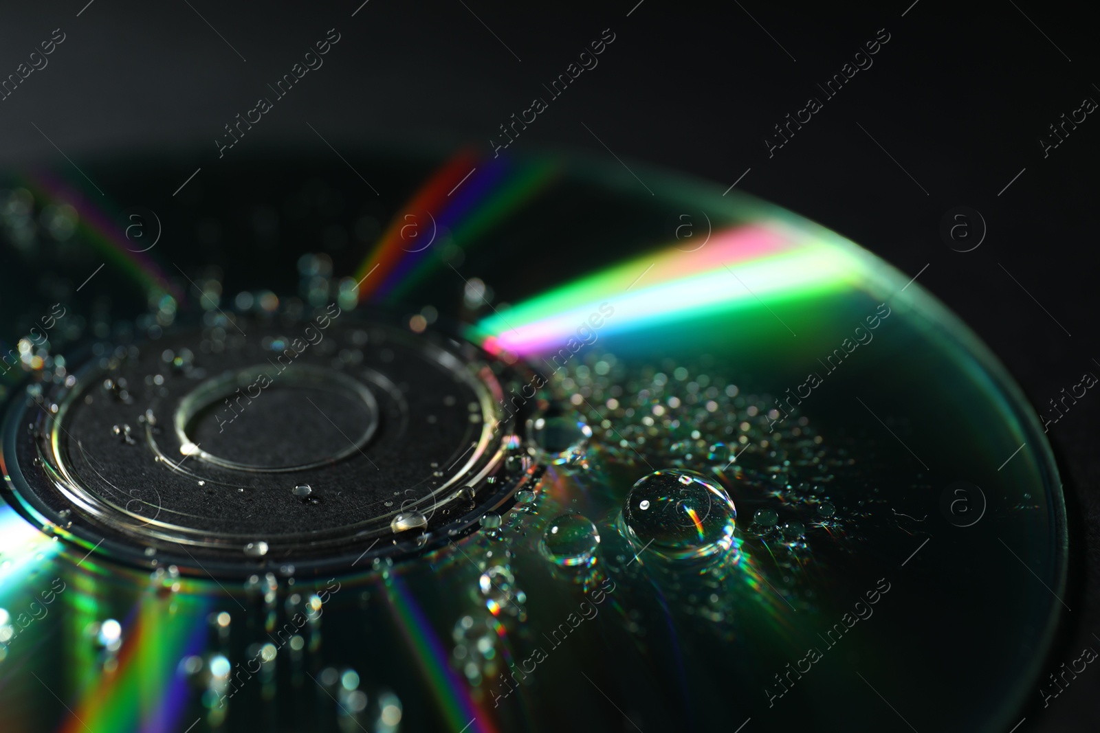 Photo of Compact disc with drops on black background, closeup view