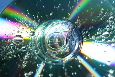 Photo of Compact discs with drops as background, closeup