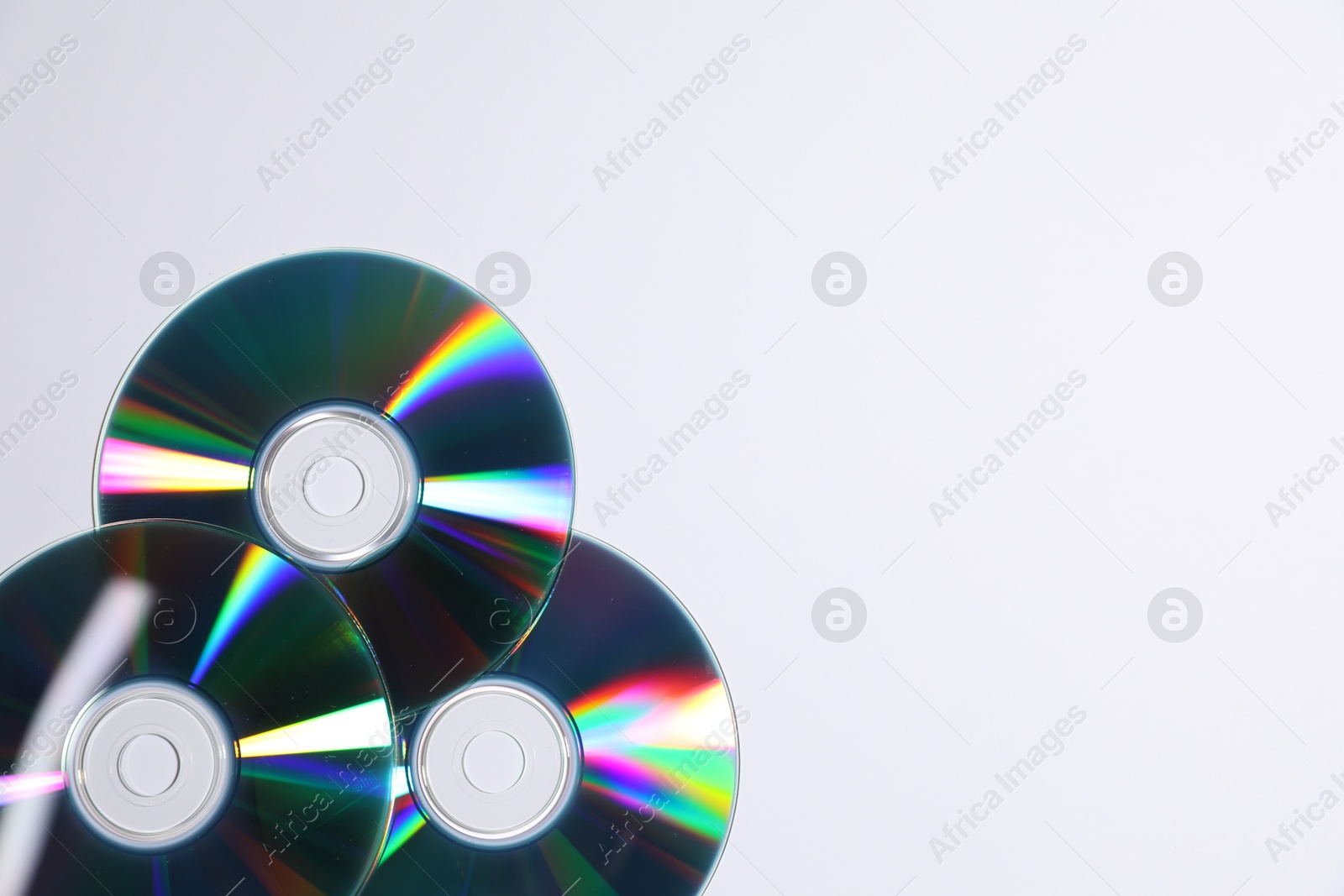 Photo of Shiny compact discs on light background, top view. Space for text