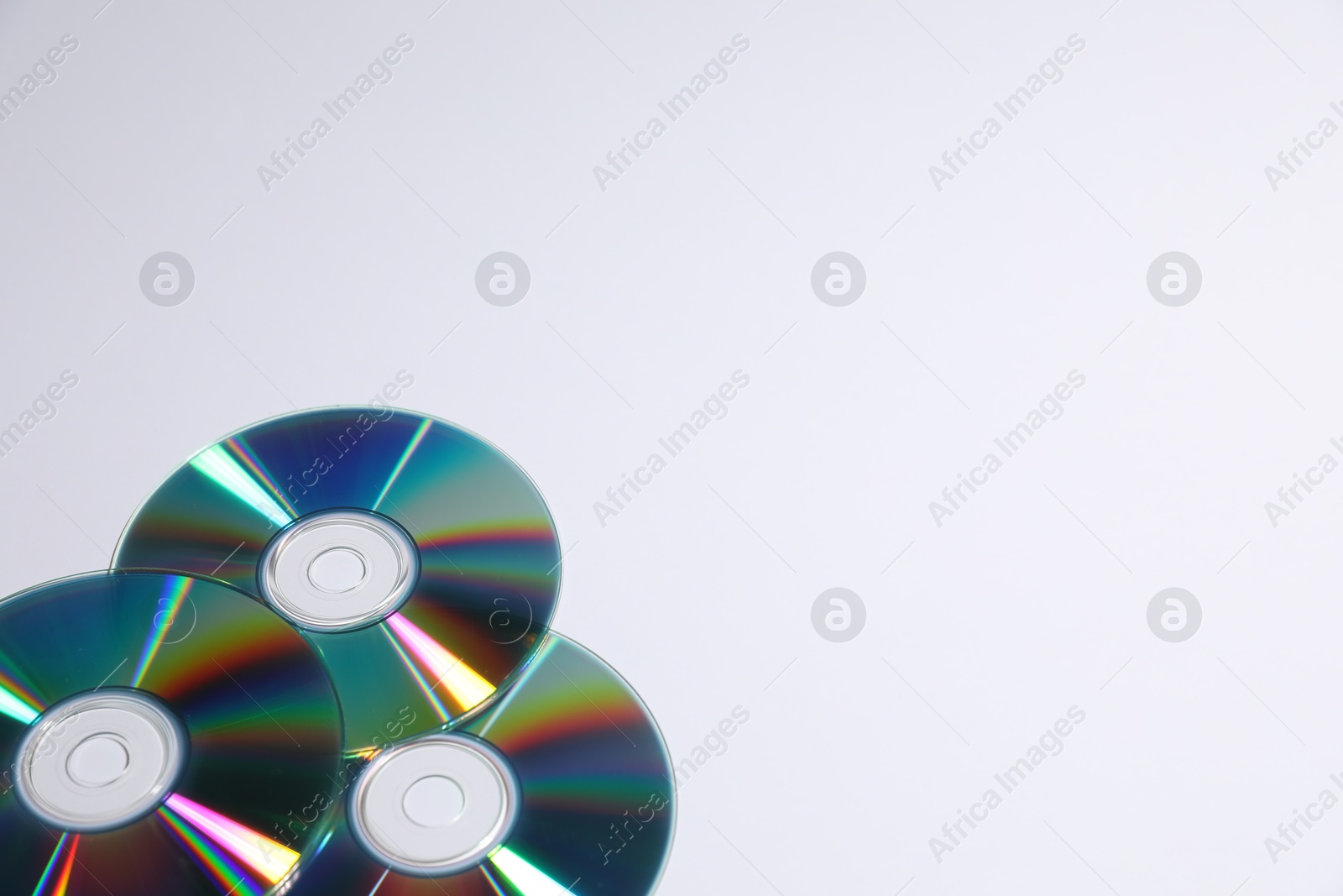 Photo of Many shiny compact discs on light background. Space for text