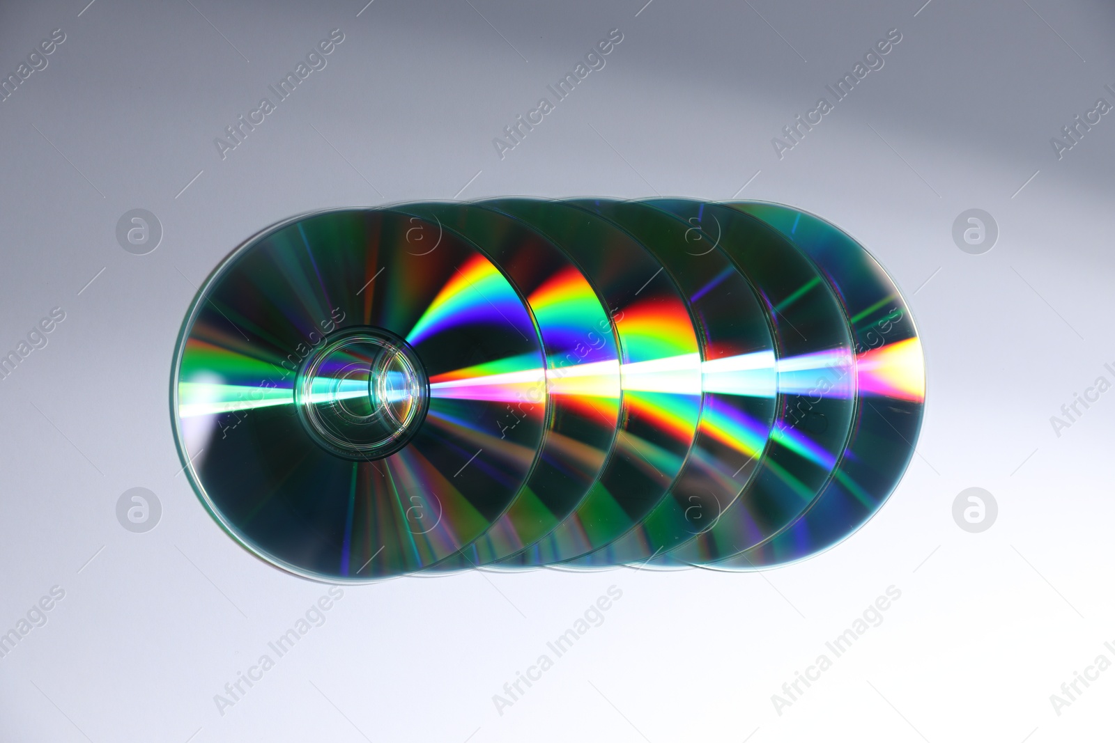 Photo of Shiny compact discs on light background, top view