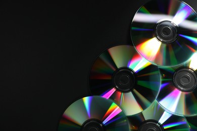 Photo of Shiny compact discs on black background, top view. Space for text