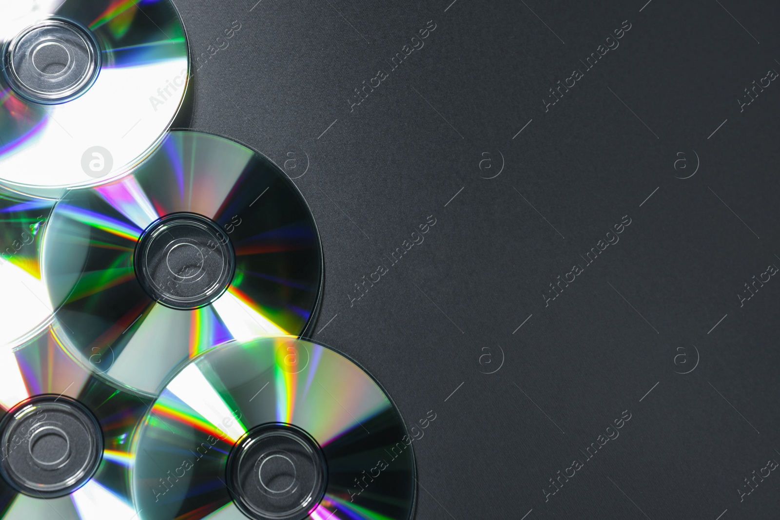 Photo of Shiny compact discs on grey background, top view. Space for text