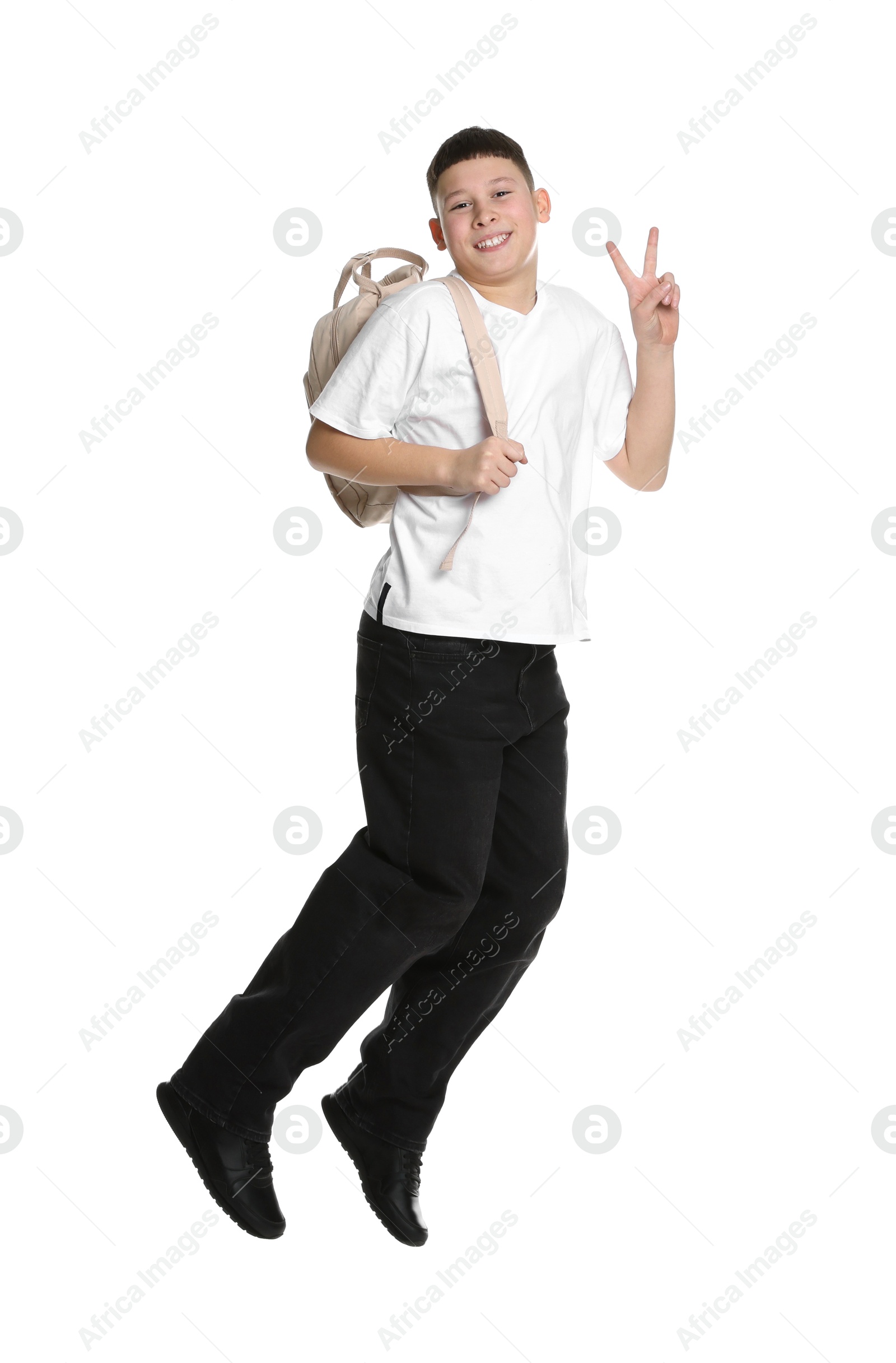 Photo of Teenage boy with backpack jumping and showing V-sign on white background