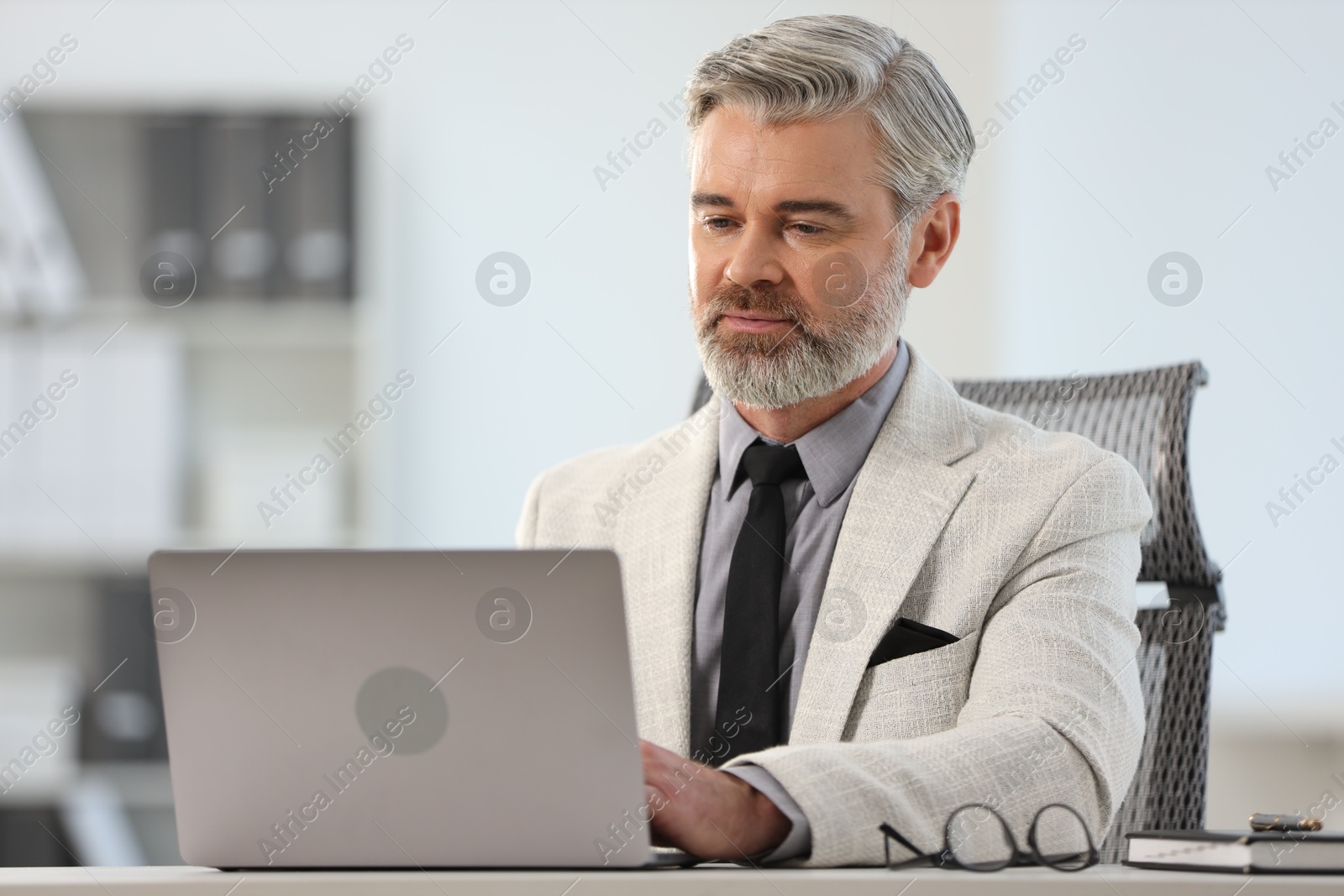 Photo of Banker working on laptop at desk in office