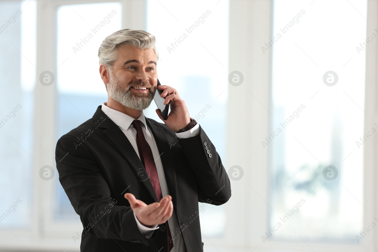 Photo of Happy banker talking on smartphone in office, space for text