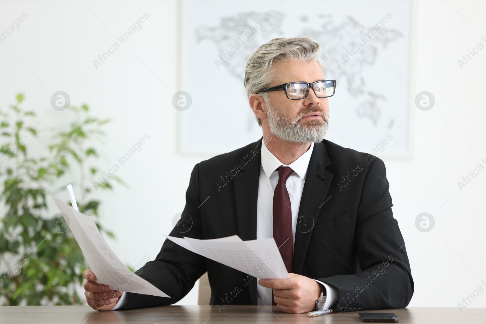 Photo of Portrait of banker with documents at desk in office