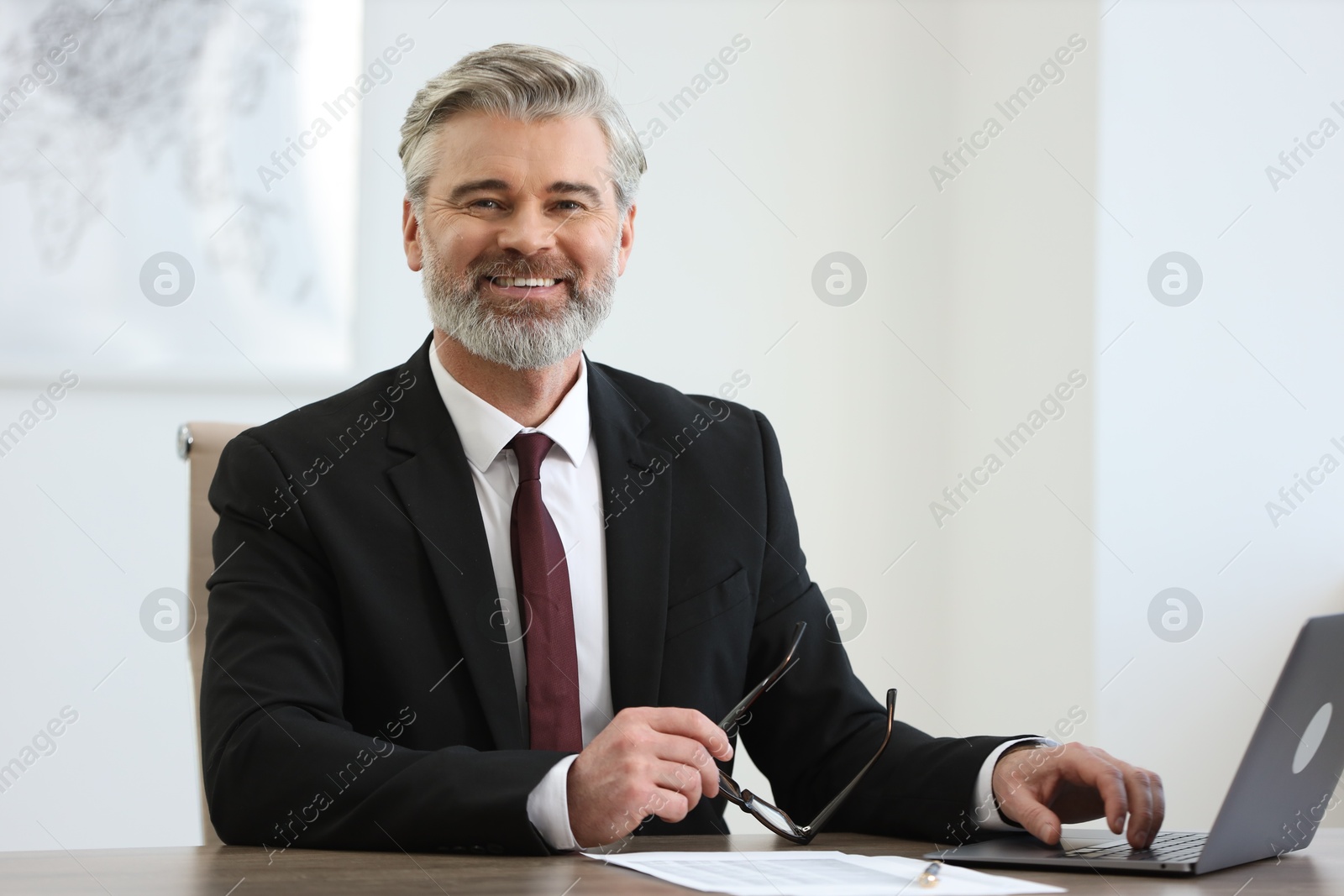 Photo of Banker with glasses working on laptop at desk in office