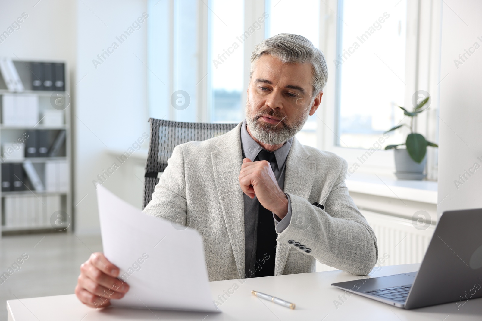 Photo of Banker with document at desk in office