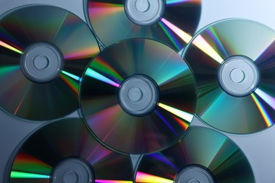 Photo of Many shiny compact discs on dusty blue background, flat lay