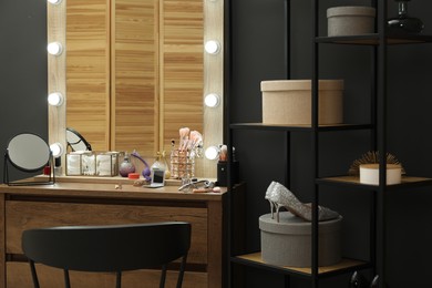 Photo of Makeup room. Mirrors, different beauty products, shoes, dresser and chair indoors