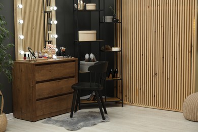 Photo of Makeup room. Mirrors, different beauty products, shoes, dresser and chair indoors