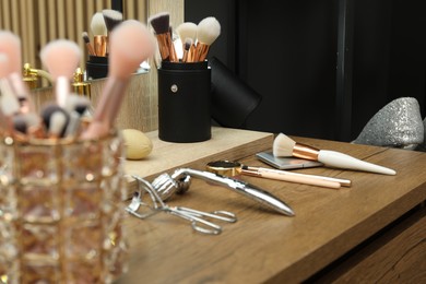 Photo of Makeup room. Different beauty products on wooden dressing table indoors, closeup