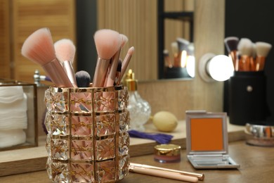 Photo of Makeup room. Brushes and different beauty products on wooden dressing table indoors, closeup