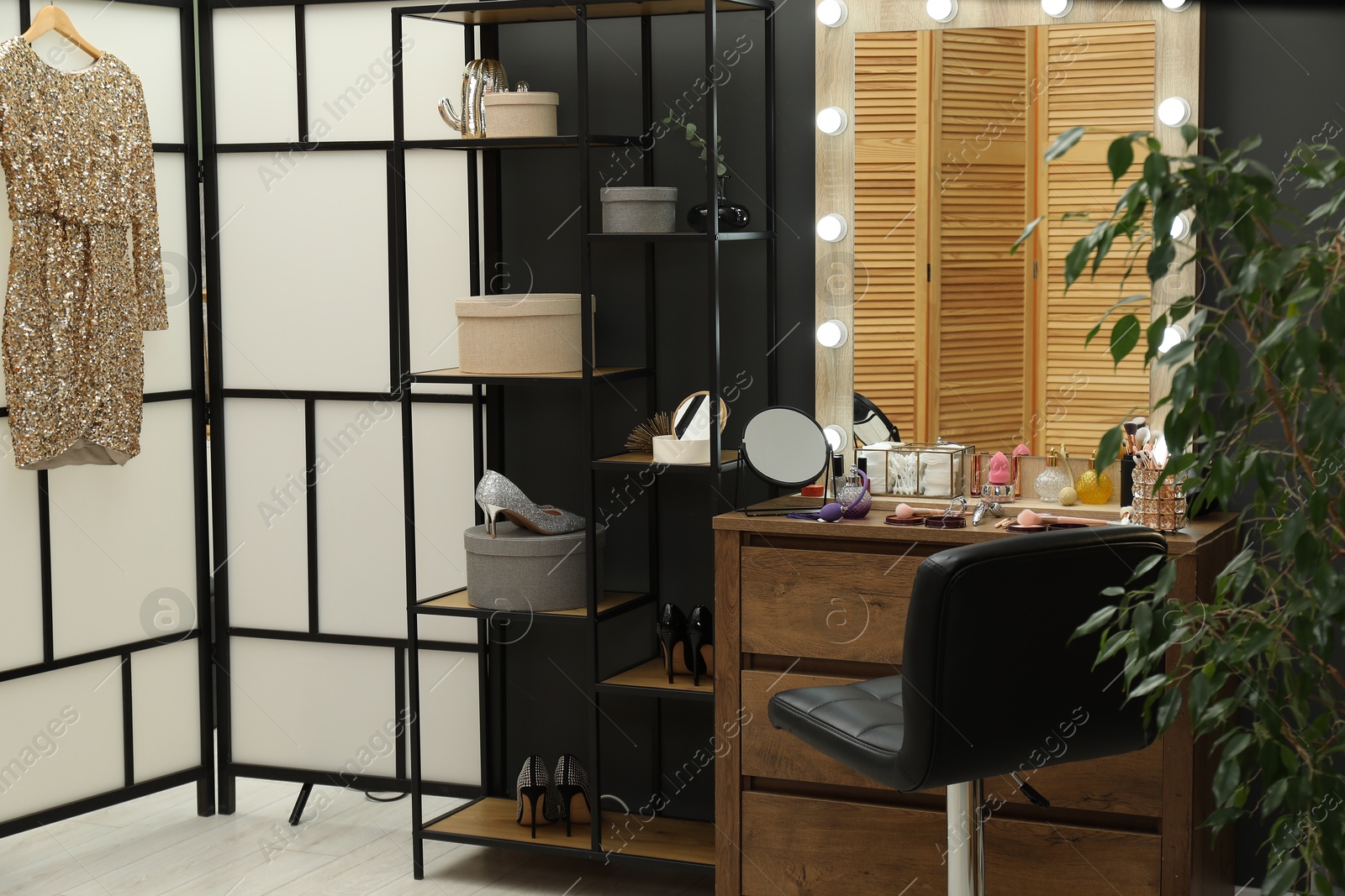 Photo of Makeup room. Wooden dresser with mirror, different beauty products, shoes and chair indoors