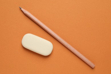 Photo of Eraser and pencil on orange background, flat lay