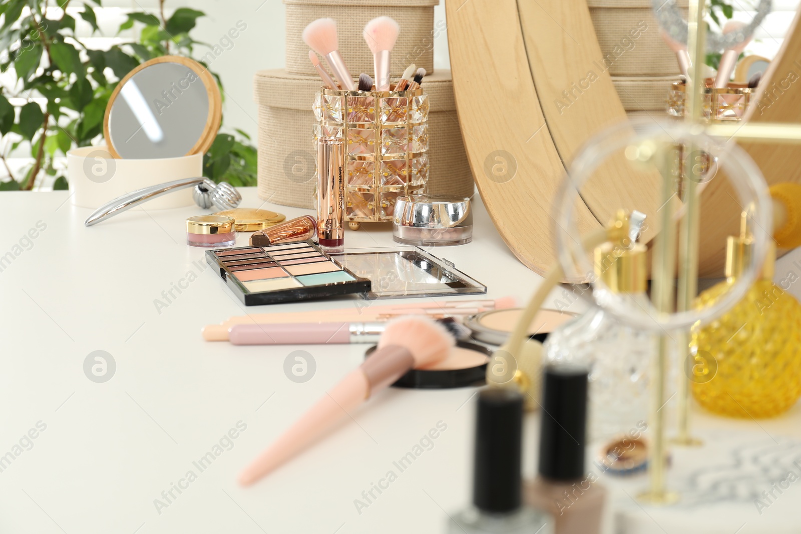 Photo of Makeup room. Mirror and different cosmetic products on white dressing table indoors, closeup