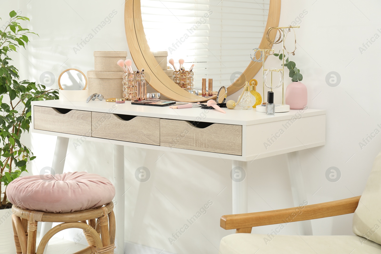 Photo of Makeup room. Dressing table with mirror, different beauty products and stool indoors